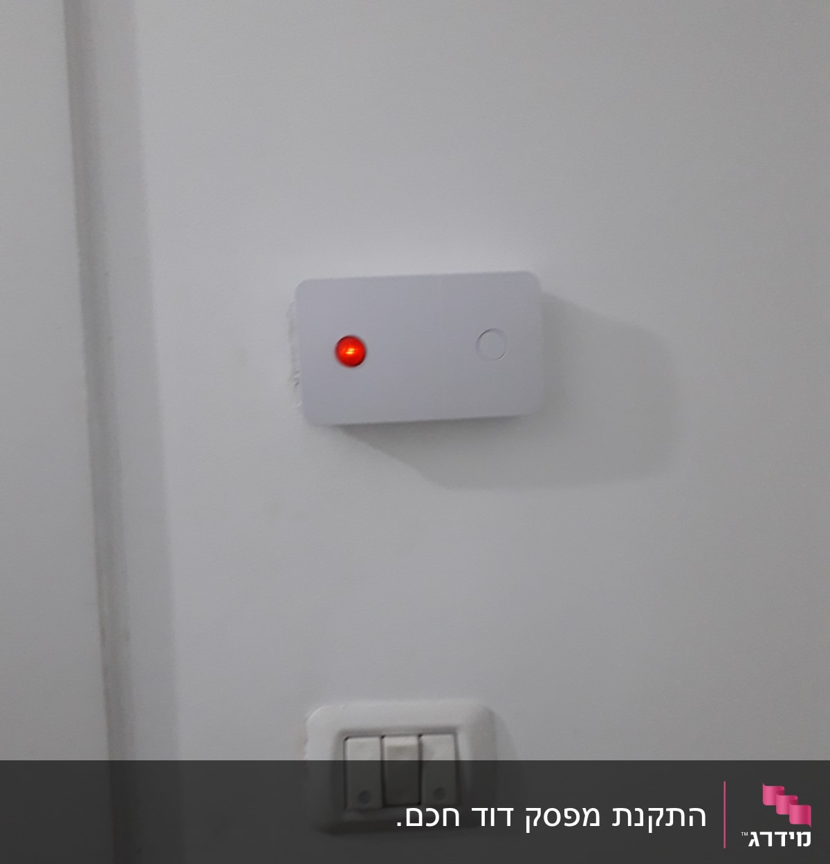 מתג חשמל עם נורית חיווי אדומה על קיר לבן